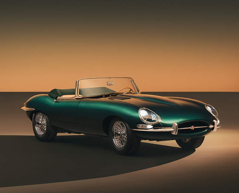 Dark green Jaguar E-Type convertible against a gradient backdrop.