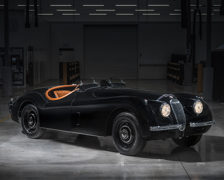Black Jaguar convertible with orange interior, parked indoors.